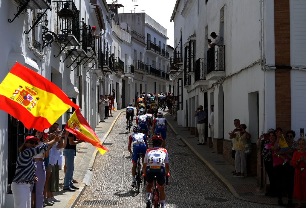 ARACENA SPAIN SEPTEMBER 07 A general view of the peloton passing through Aracena start village while fans cheer during the 77th Tour of Spain 2022 Stage 17 a 1624km stage from Aracena to Monasterio de Tentuda 1095m LaVuelta22 WorldTour on September 07 2022 in Aracena Spain Photo by Justin SetterfieldGetty Images