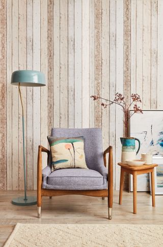 A textured grey and wood armchair and muted green lamp against a wood-style panelled background