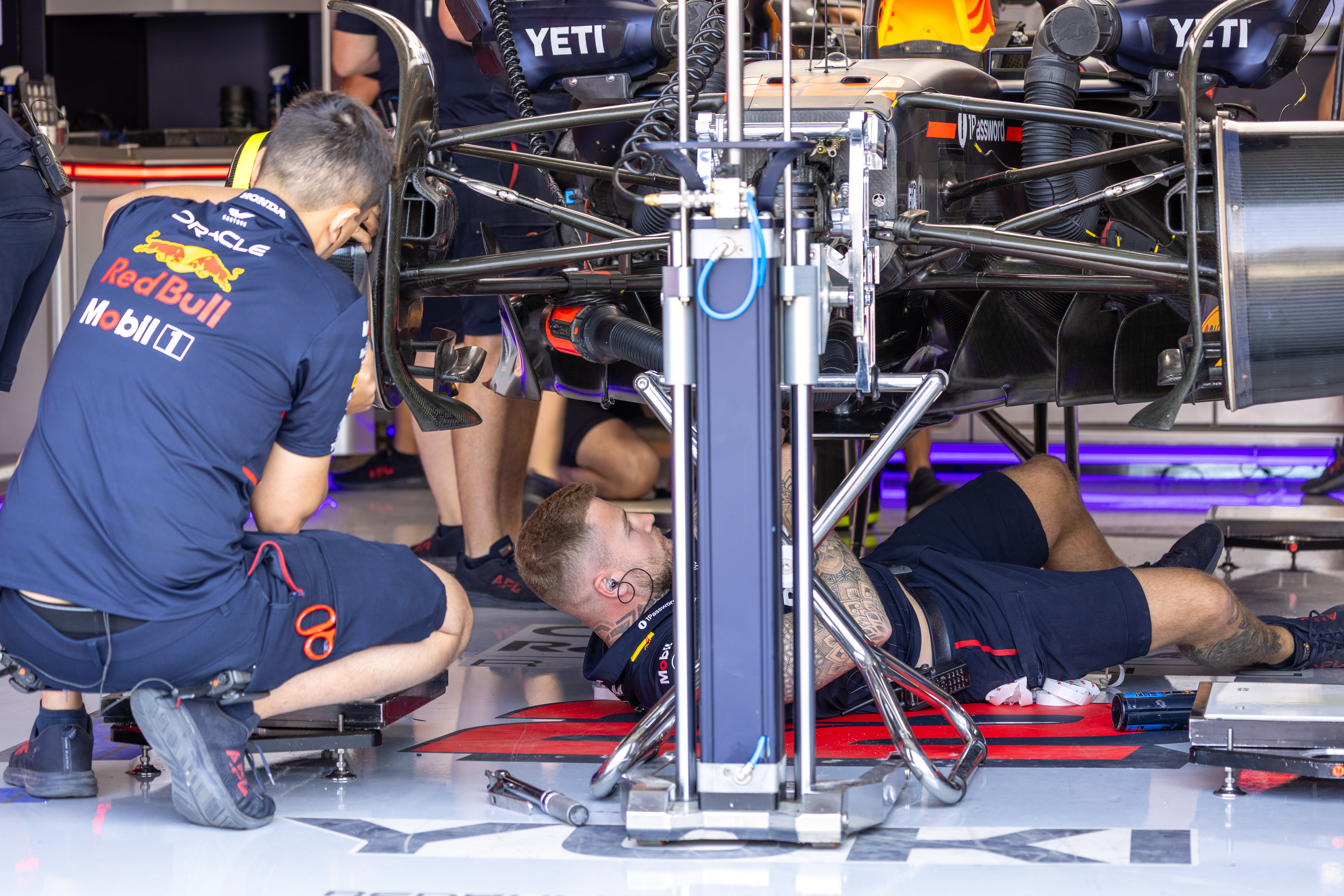Red Bull mechanics fix the underside of a F1 car