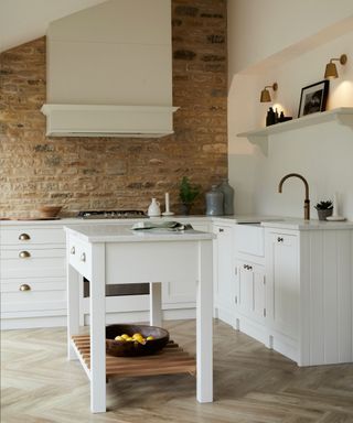 Small white shaker farmhouse kitchen by Olive & Barr with exposed stone wall