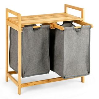 Two seperate gray fabric laundry hampers in a wooden frame with a top shelf. 