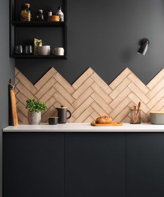 High contrast kitchen design with black walls and cabinets, and taupe metro tile backsplash in zig-zag formation.