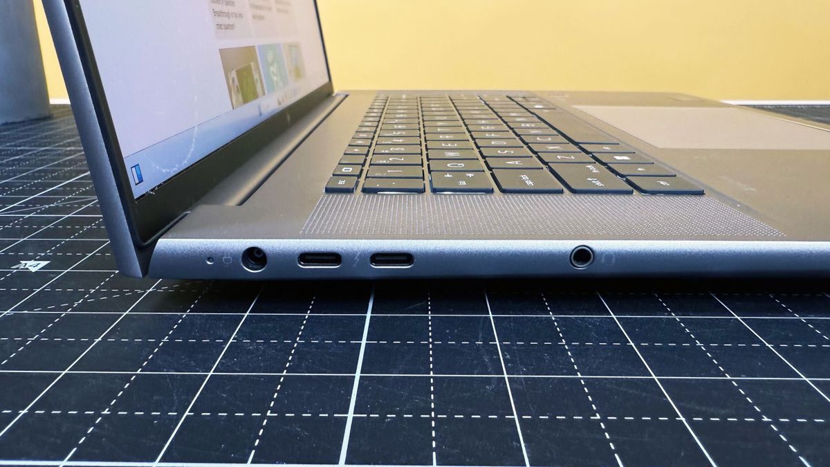 Close up of the left-side ports on the HP ZBook Studio 16 G11 mobile workstation on a white desk with a black table mat, against a yellow backdrop.