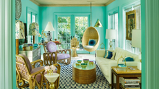 Tiffany blue-drenched living room with geometrically tiled floors featuring an eclectic mix of rattan furniture and brass accents. 