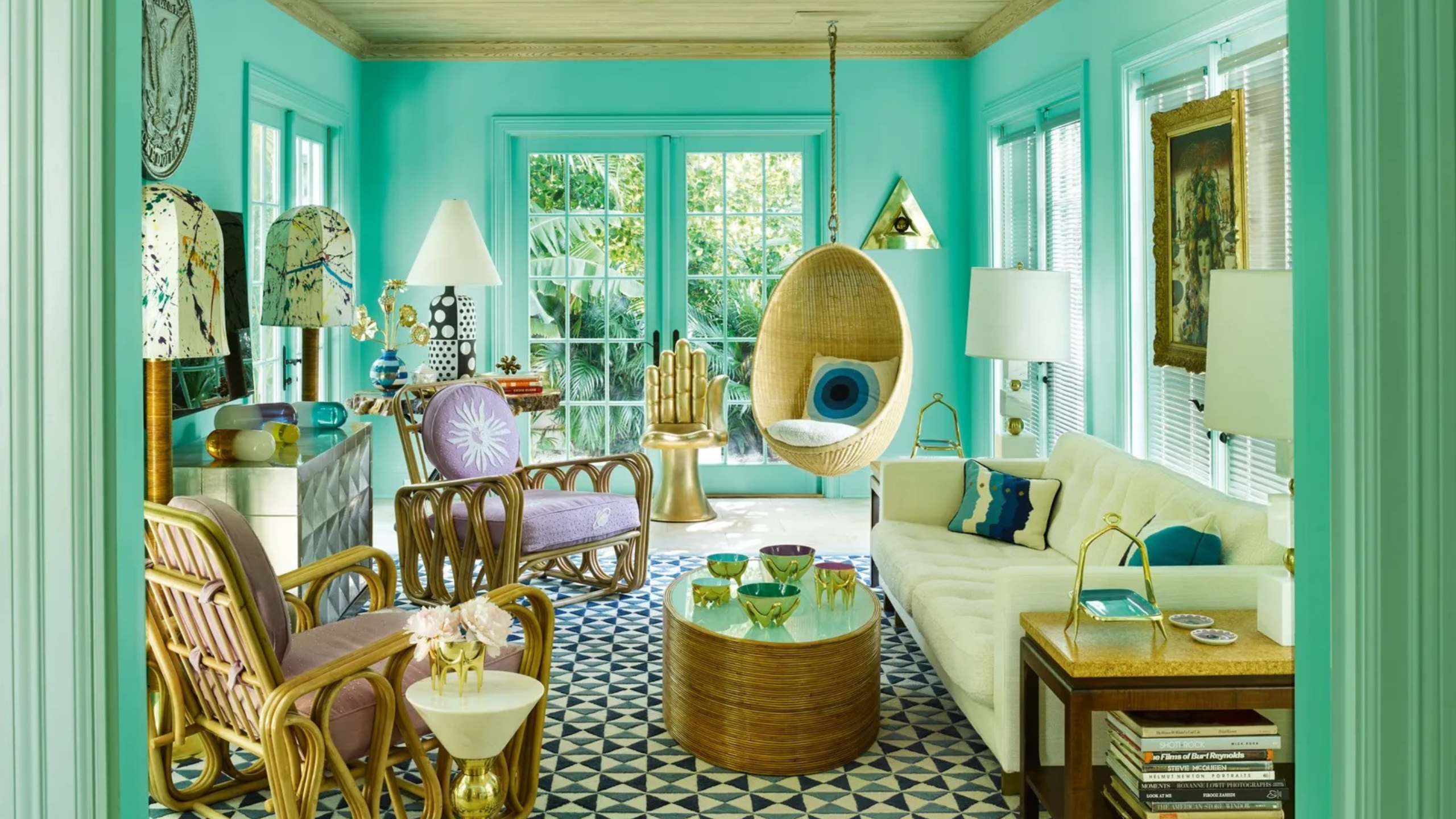Tiffany blue-drenched living room with geometrically tiled floors featuring an eclectic mix of rattan furniture and brass accents. 