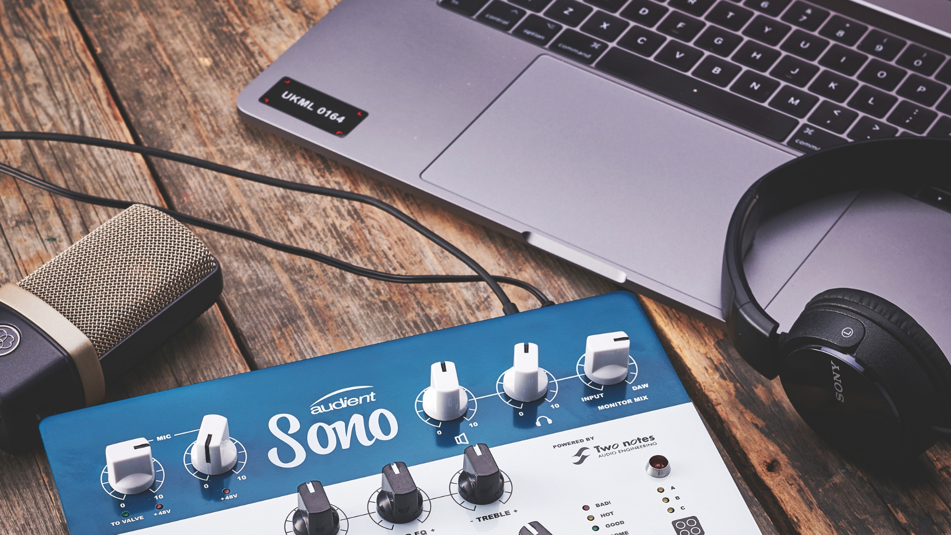 A pair of headphones with a guitar pedal, laptop, and a microphone