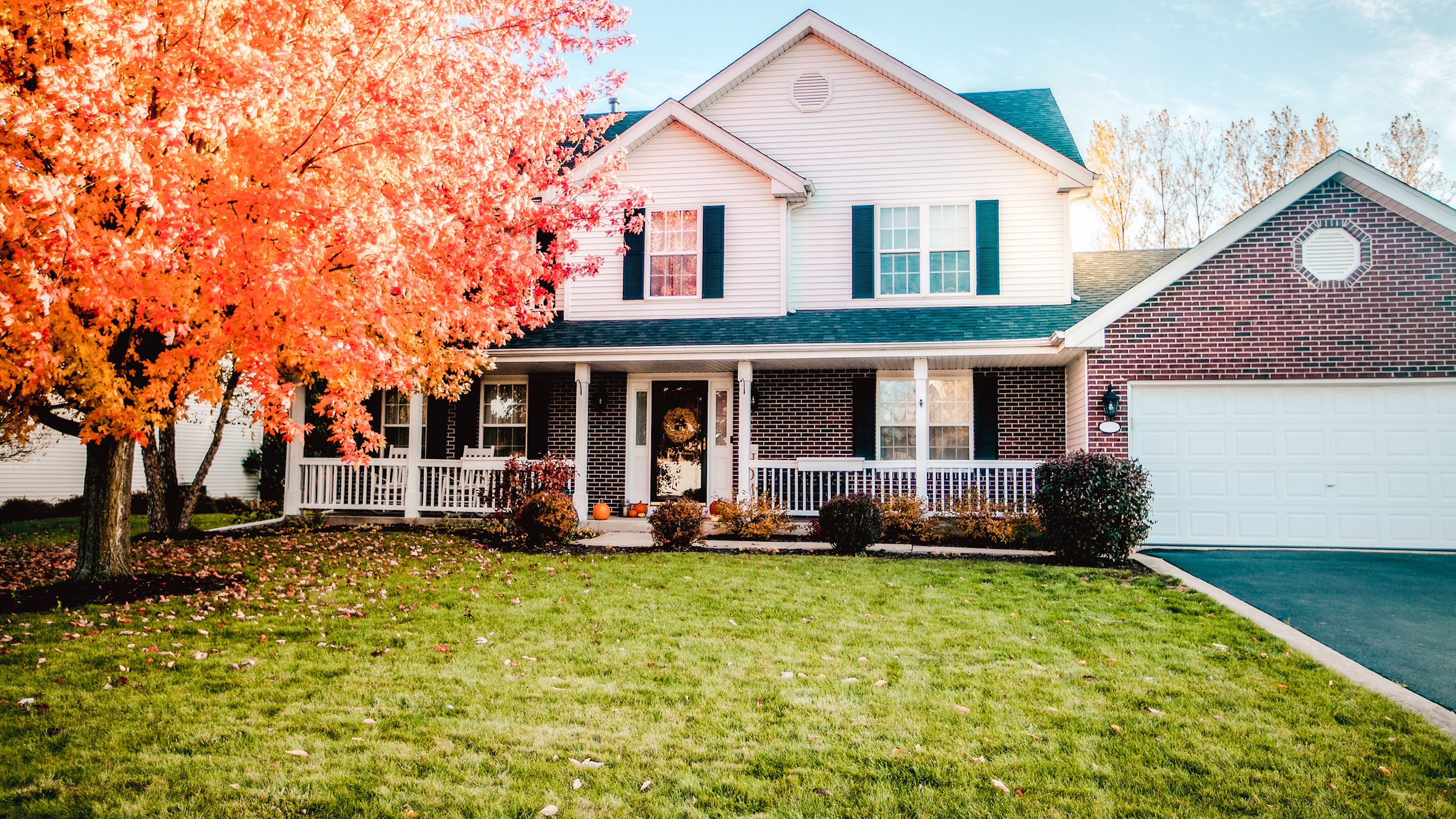 A two-storey house with a green front lawn in fall 
