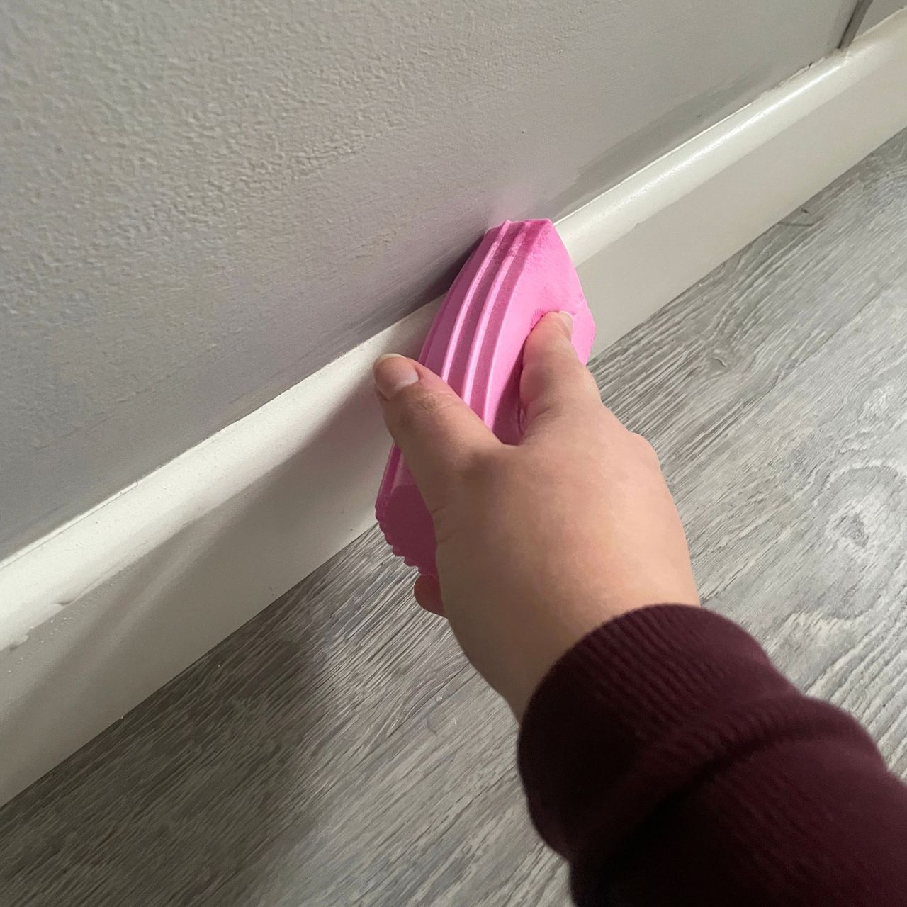 Using a pink Damp Duster to dust white skirting boards