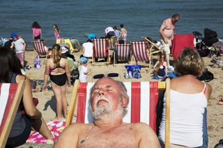 Red-faced man sleeping on a deckchair on the beach