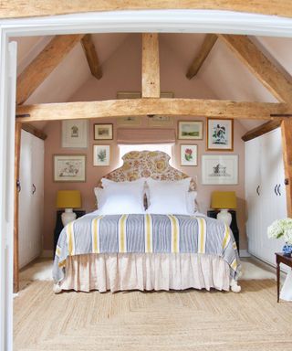 bedroom with vaulted ceiling and pale pink walls in Sarah Vanrenen Wiltshire country barn