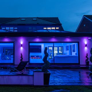 Purple smart wall lights from 4lite outside house in garden