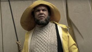 A bearded John C. Reilly dressed in a raincoat holding and sweater in the SNL Digital Short "Harpoon Man"