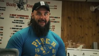 Braun Strowman in a blue t-shirt and baseball cap excited about food and staring straight at the camera on Everything on the Menu. 