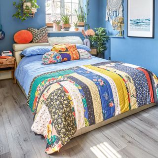 Blue-painted bedroom with patchwork bedding and large dreamcatcher on wall