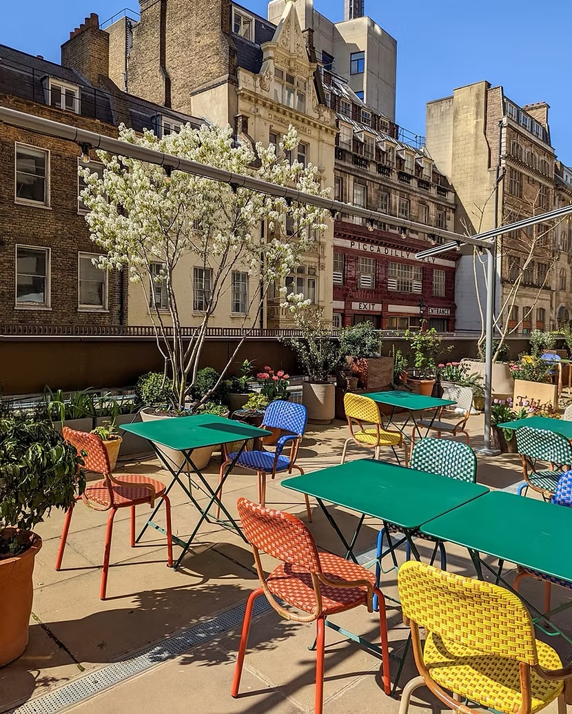 Brightly coloured tables and chairs on a paved London terrace with Georgian buildings in the background