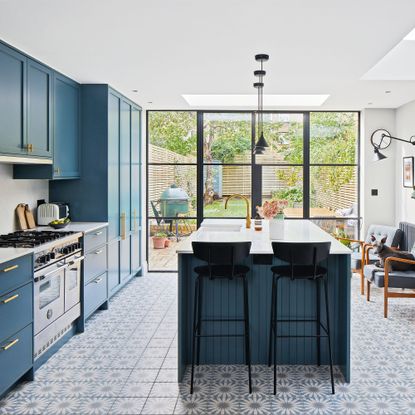 A bright kitchen with teal blue cupboards and a patterned tile floor