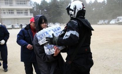 A U.S. naval air crewman delivers bottled water to a Japanese citizen after the earthquake.