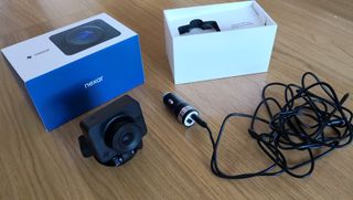 A dash cam surround by accessories on a wooden table