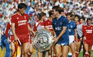 Liverpool captain Alan Hansen and Everton captain Kevin Ratcliffe carry the Community Shield after the two sides drew to share it, 1986