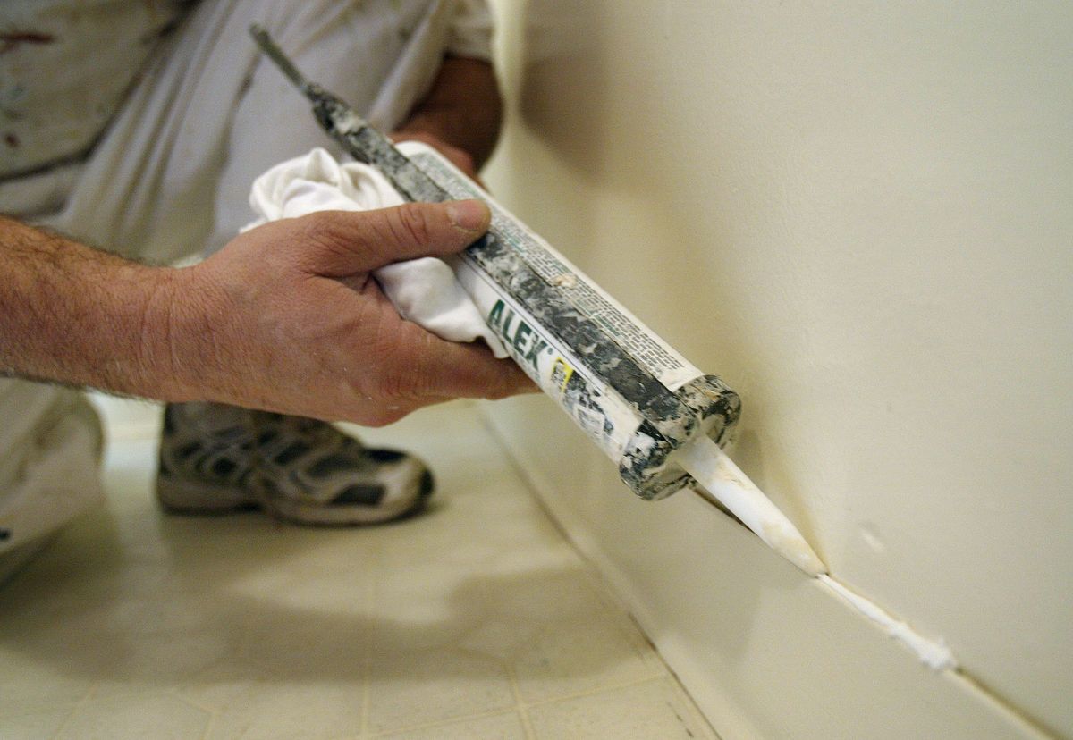 A man caulking skirting board