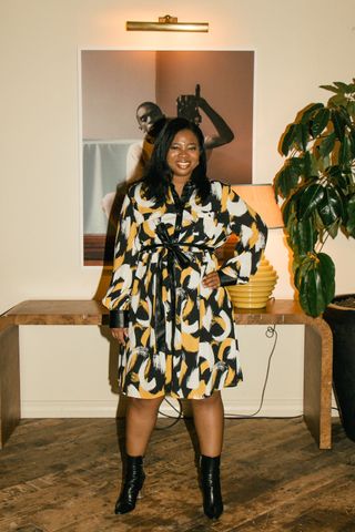 Brittney Oliver in a black, yellow, and white dress featuring black boots.