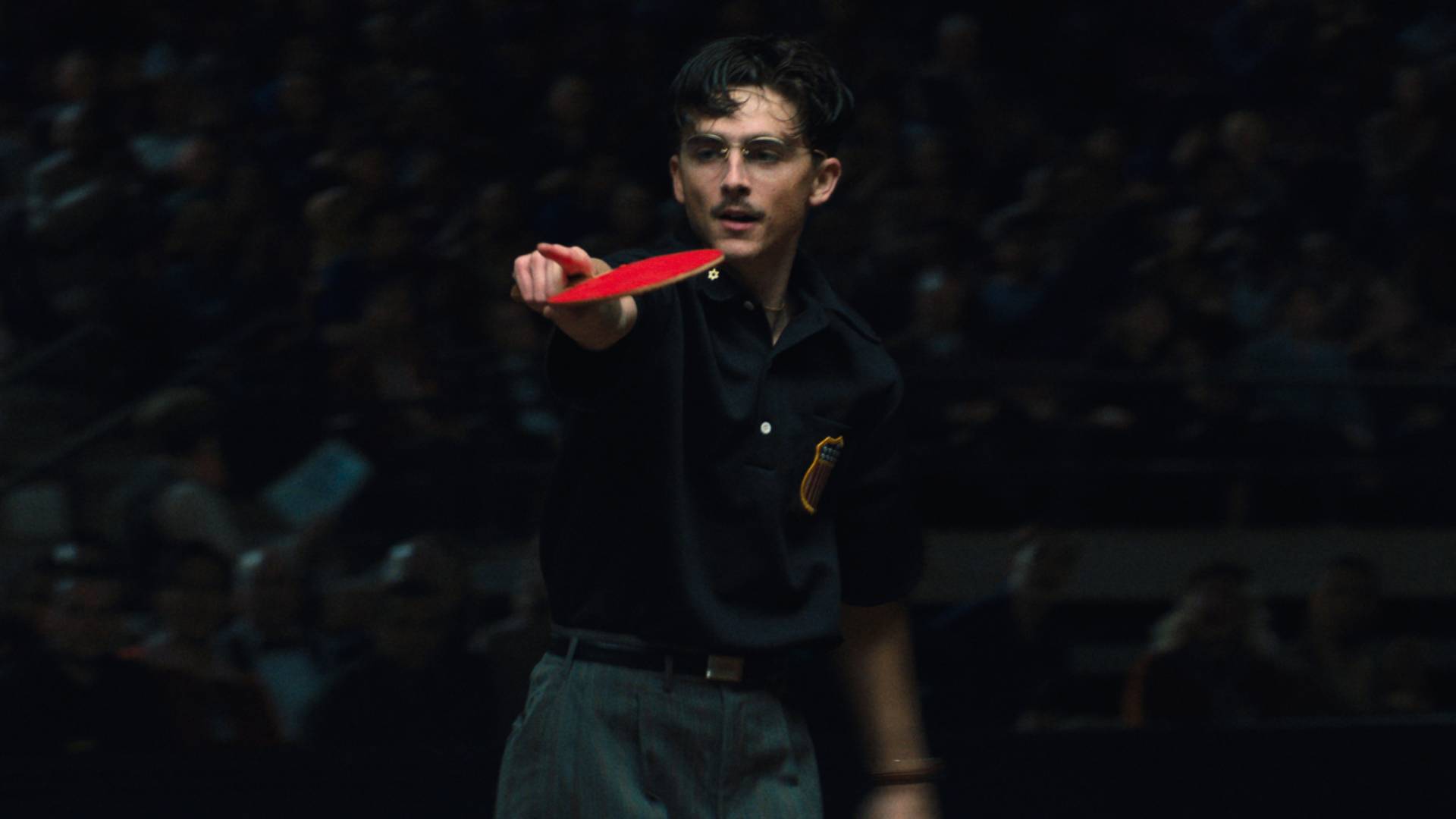 Timoth&eacute;e Chalamet as Marty Supreme, holding a ping pong paddle and pointing