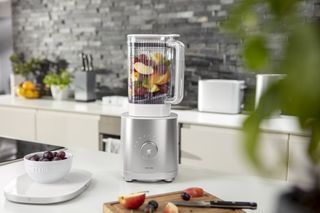 a blender on a kitchen worktop filled with fruit