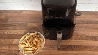 The Proscenic T22 Air Fryer with the drawer partially removed, next to a plate of homemade fries