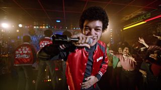 Justice Smith smiles with the mic in the middle of a show in The Get Down S1 E9 - "One by One, Into the Dark."