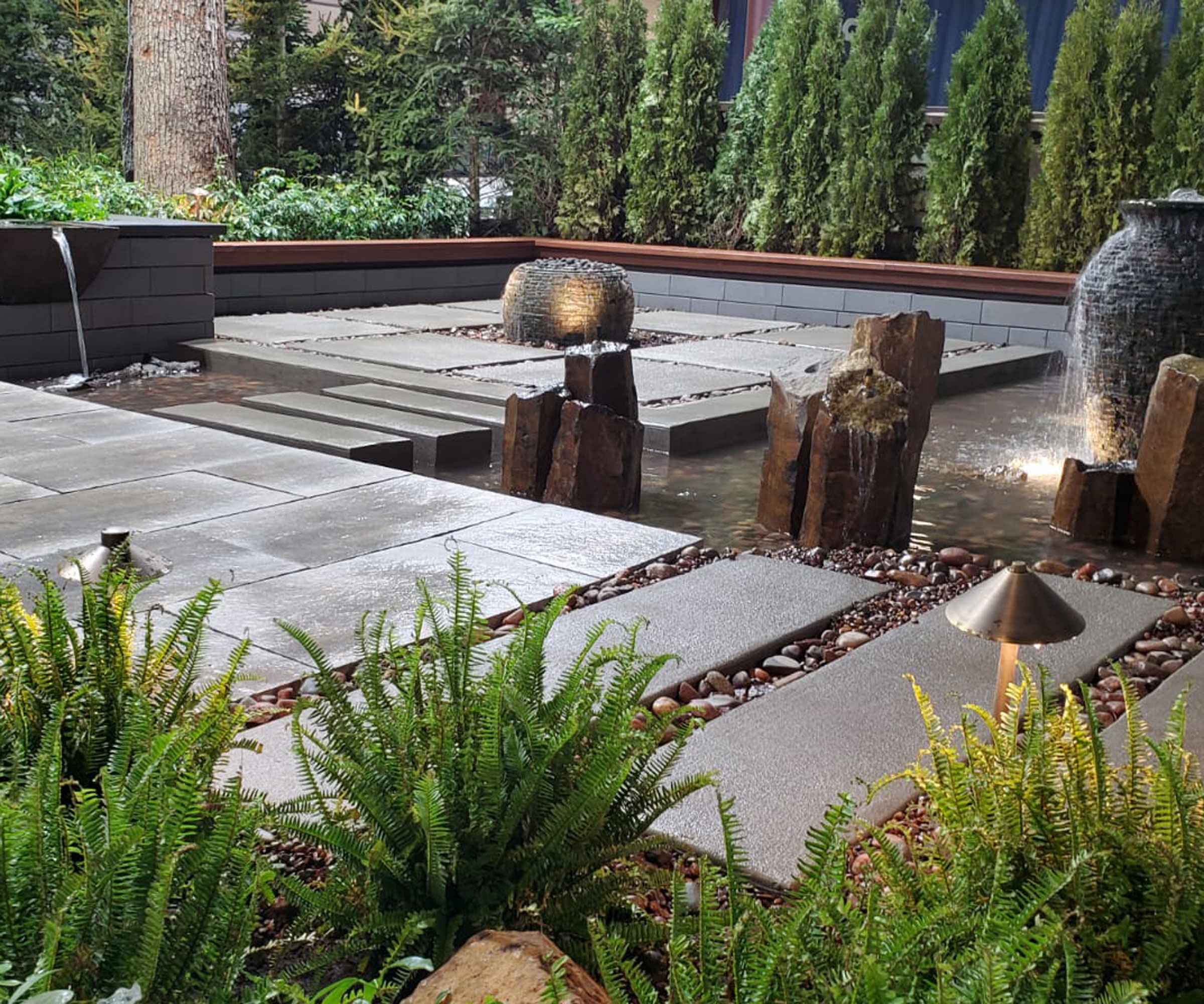 modern water garden with water shute, trickling fountain, river rocks, pavers and ferns