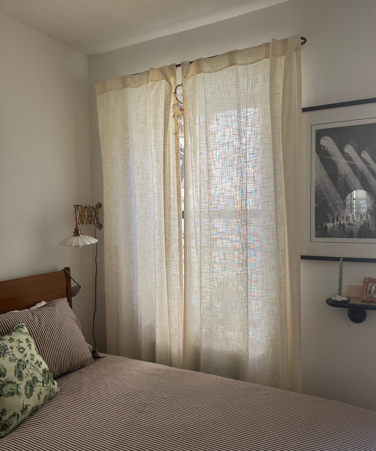 a bedroom with sheer curtains in front of the windows