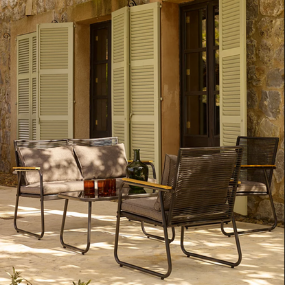 George Home Lisbon dining se on a patio in front of green french doors.