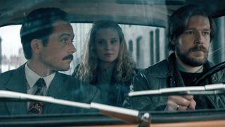 (L to R) Taron Egerton as Henk Rogers, Sofia Lebedeva as Elena and Nikita Efremov as Alexey Pajitnov, all in a car together, in Tetris