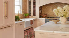 pink kitchen with gold hardware and an arched stove