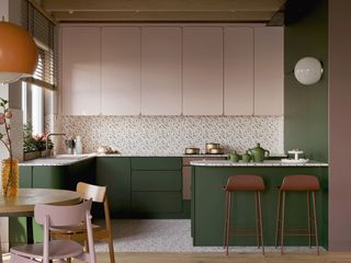 image of a kitchen with light pink and dark green cabinetry