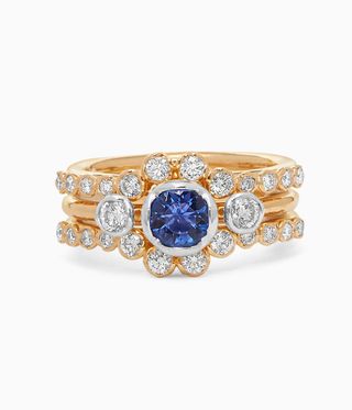 Multiple stack of gold rings surrounding a central one with big blue stone and diamonds