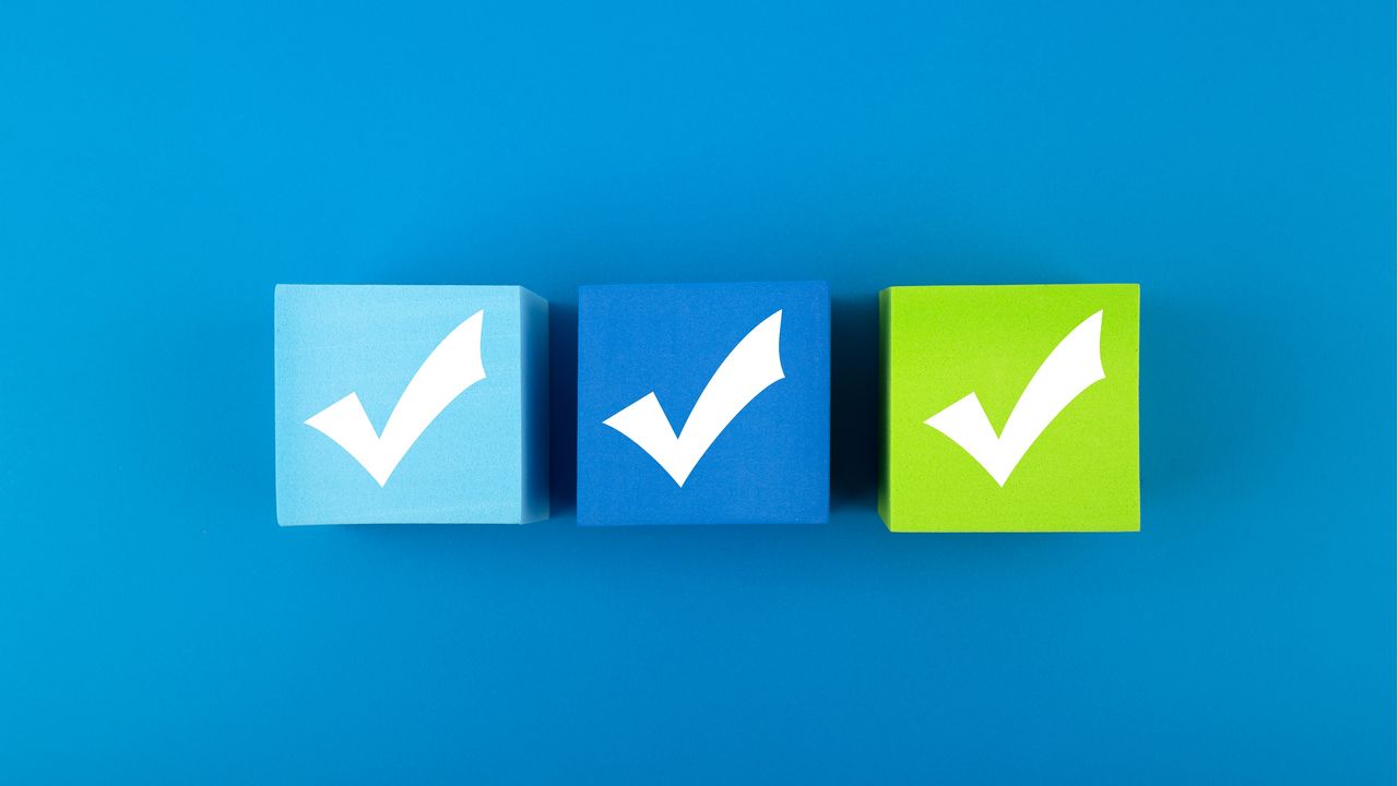 Three colorful wooden blocks with checkmarks on them against a blue background.