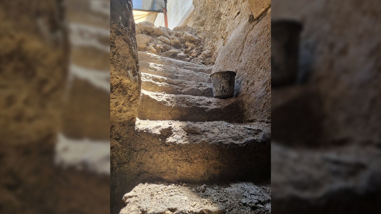 Several steps cut into limestone. There is a black bucket on one of the steps.