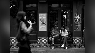 Two people read a menu outside of a pub, while another person walks past in the foreground