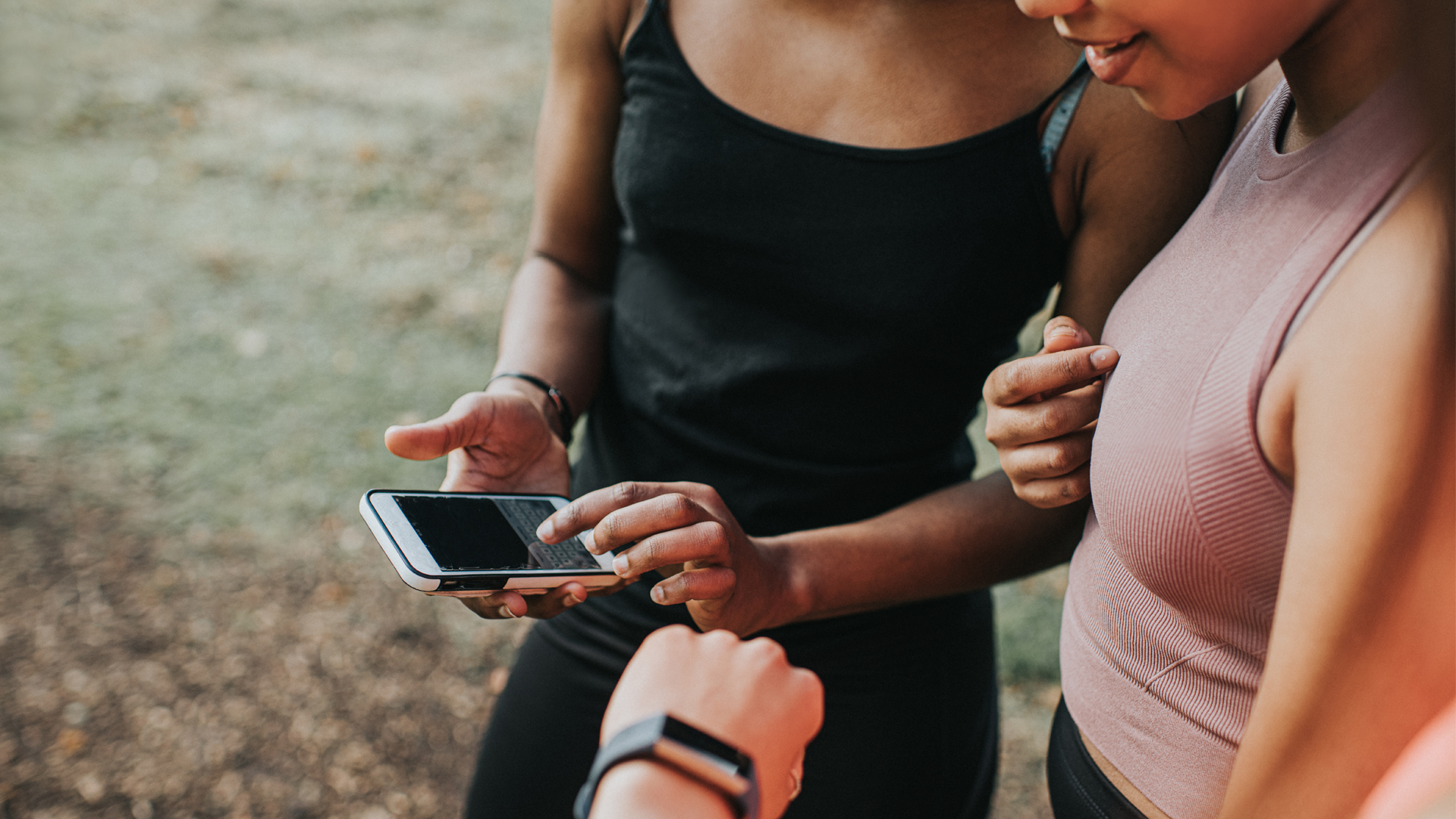 Three women checking a fitness tracker and app