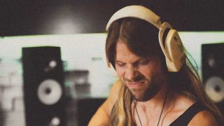 Kenny Leckremo in the studio wearing headphones, playing guitar