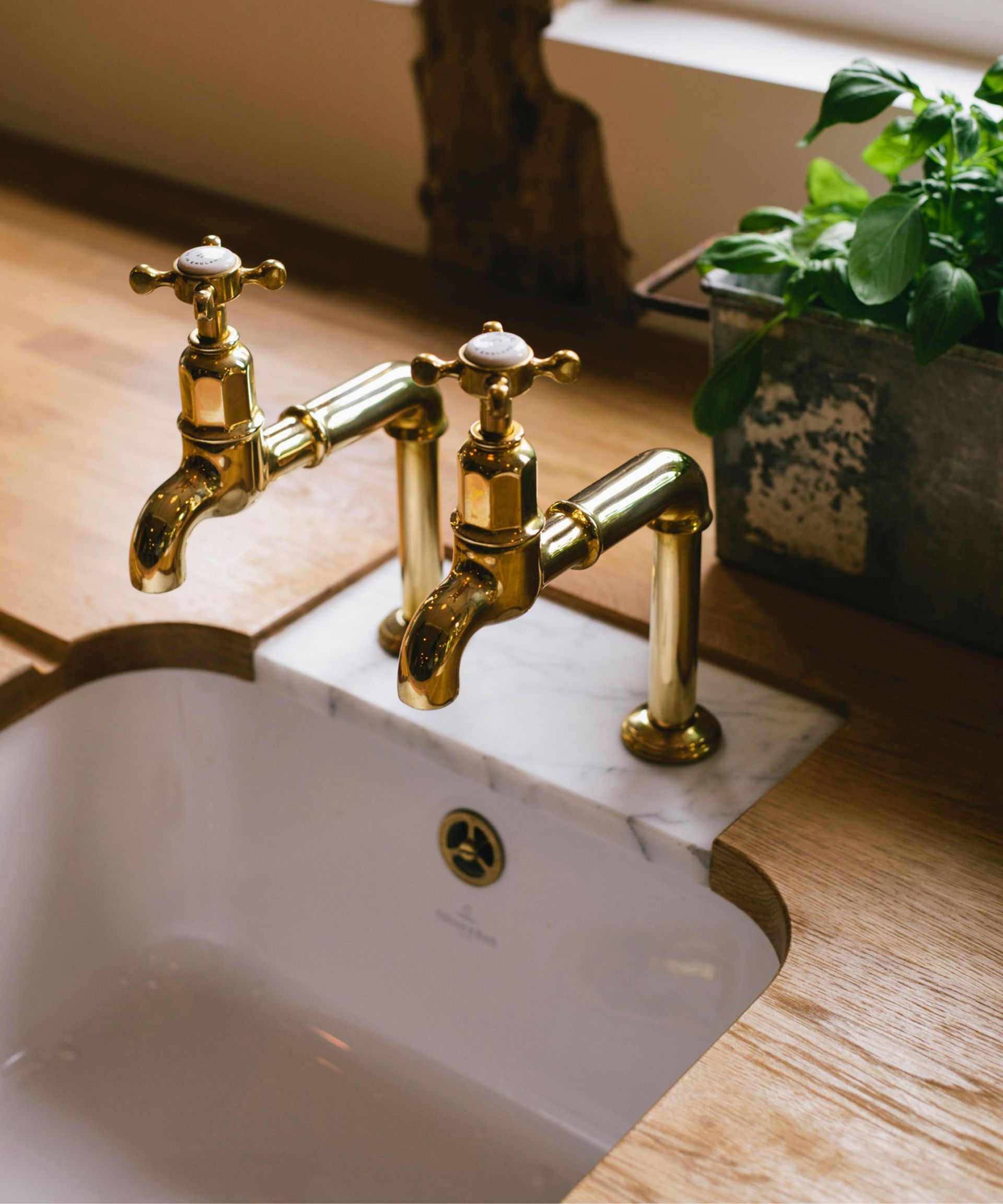 brass devol kitchen taps vintage style on a wooden butcher block countertop with a small marble insert that the taps sit on