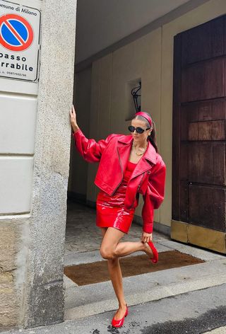 a photo of a woman wearing a red dress with red ballet flats and a matching leather jacket, what shoes to wear with a red dress