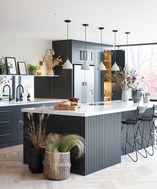 Black kitchen cabinets and island in modern kitchen space with white island and decorative pieces