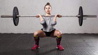 Woman performs front squat exercise with barbell