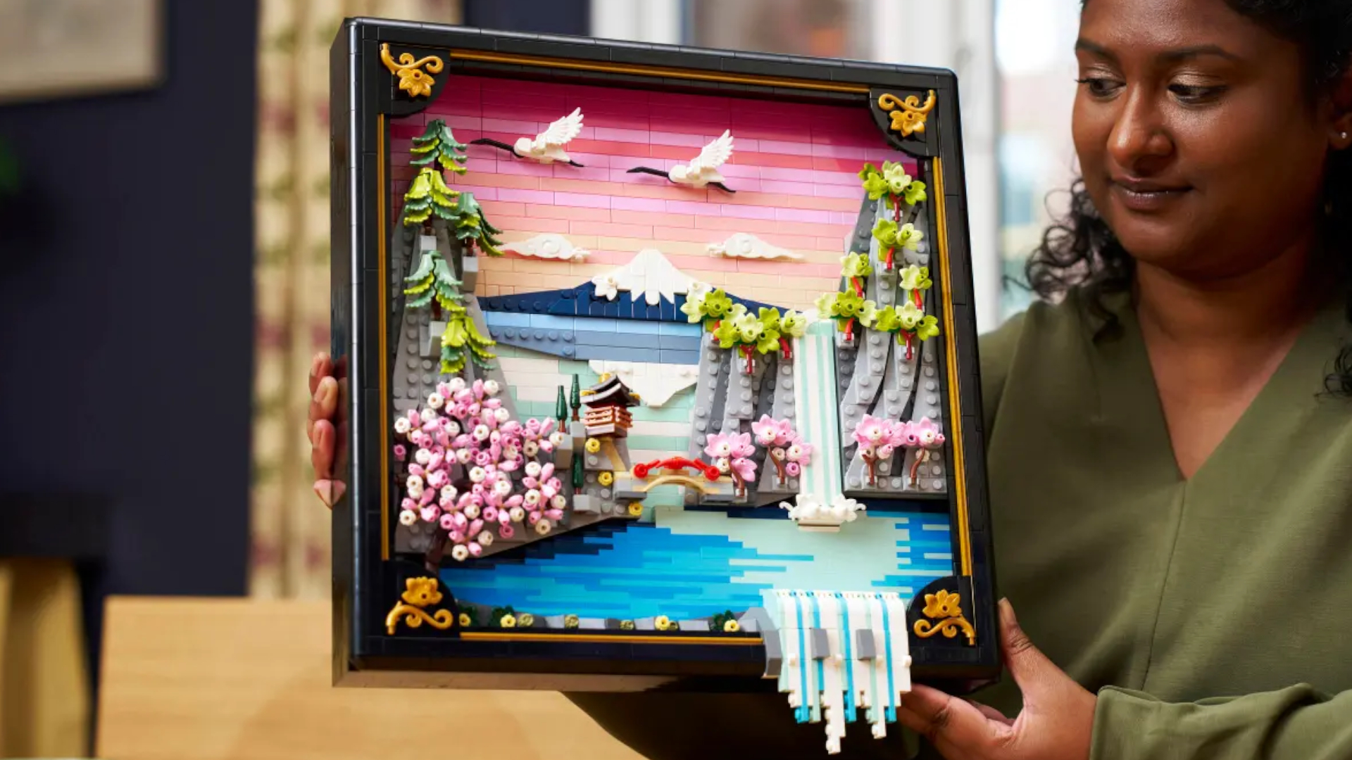 A woman holding up the Lego Japanese Cherry Blossom Landscape set while smiling