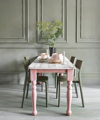 Green dining room with chalky pale green painted panels, pink dining table,