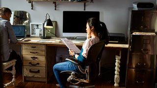 A woman sits in front of a computer and looks over her financial forecast