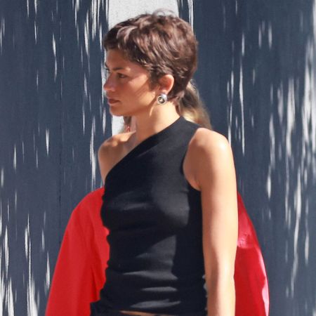 Zendaya wears black moto boots with a black skirt and a one-shoulder tank top