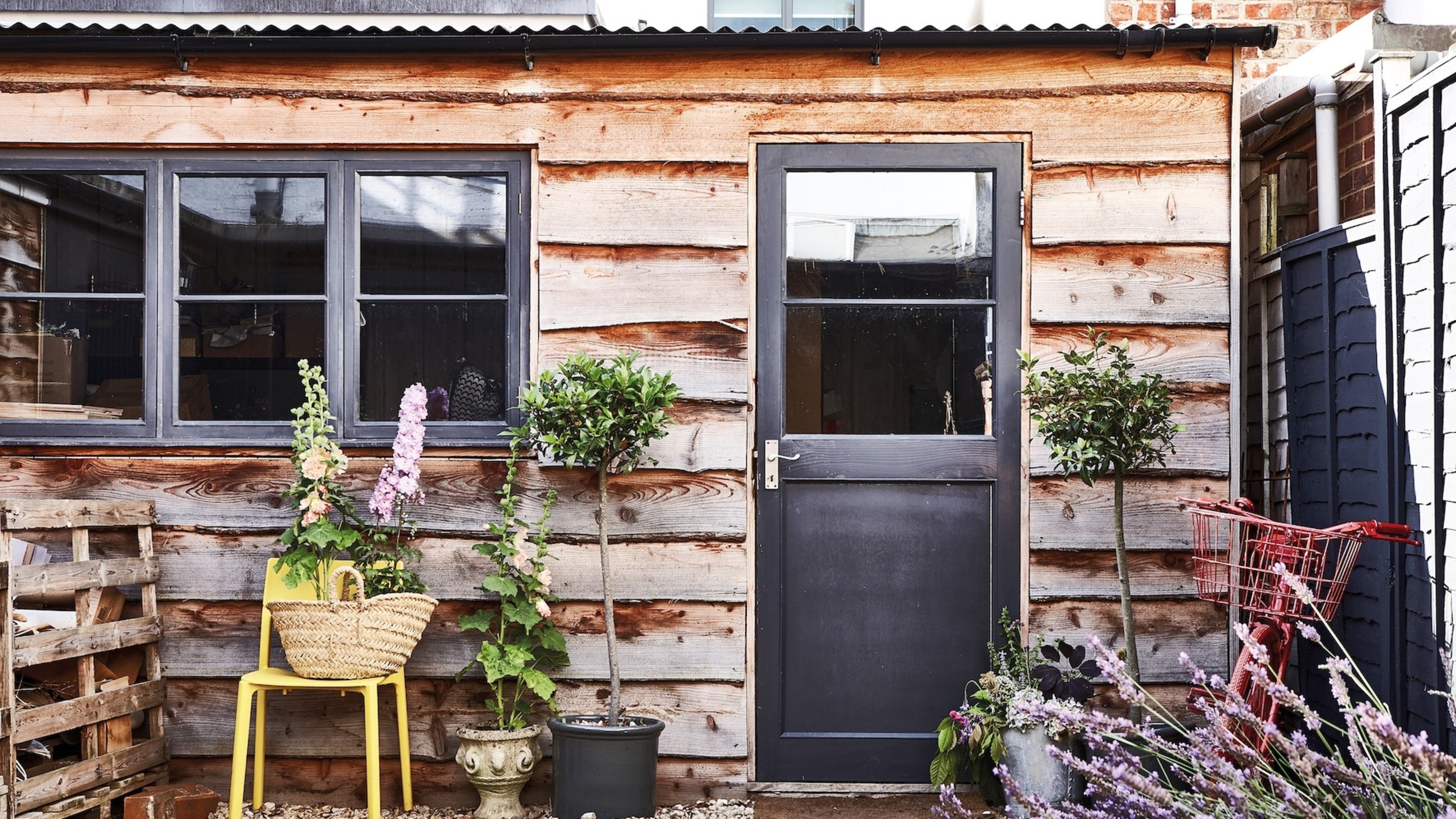 exterior of a timber shed with a black door and window frames